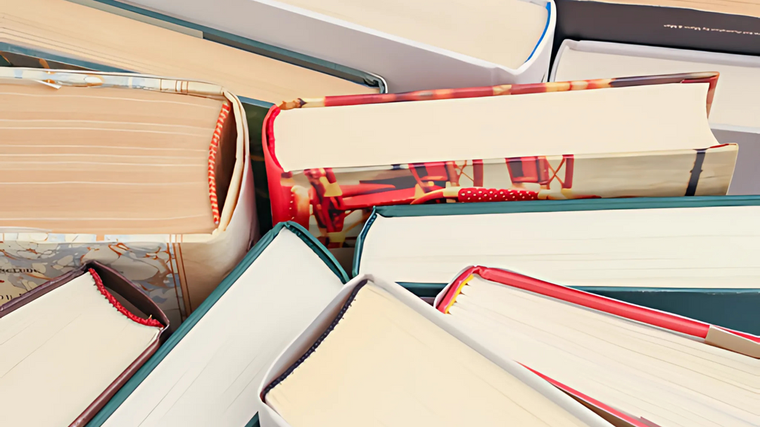 A close-up of a variety of books stacked together, showing different cover designs, colors, and textures.