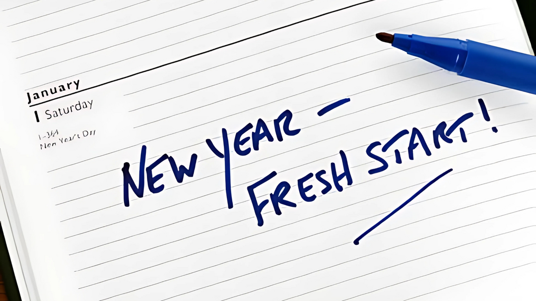 A planner opened to January 1st with a blue marker writing "New Year - Fresh Start!" in bold, underlined handwriting.