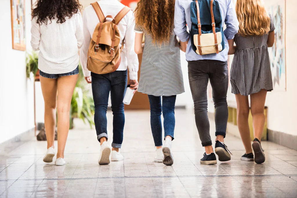 Group of students with backpacks walking down a corridor.