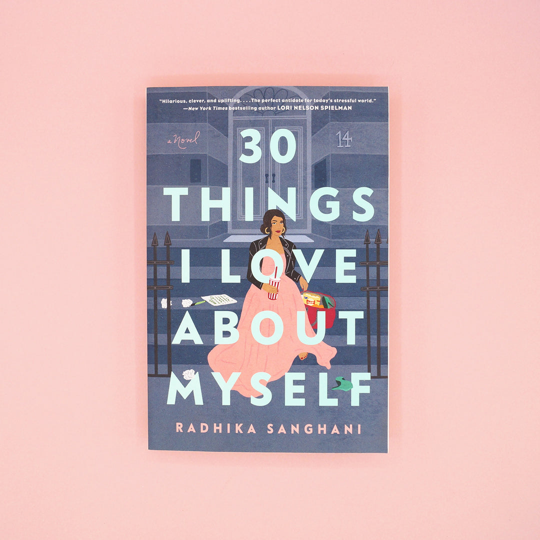 A paperback copy of 30 Things I Love About Myself by Radhika Sanghani sits on a pink background.