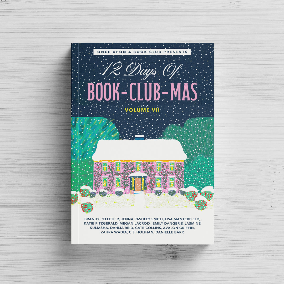 A paperback copy of the 12 Days of Book-Club-Mas Volume VII sits on a white wood background.