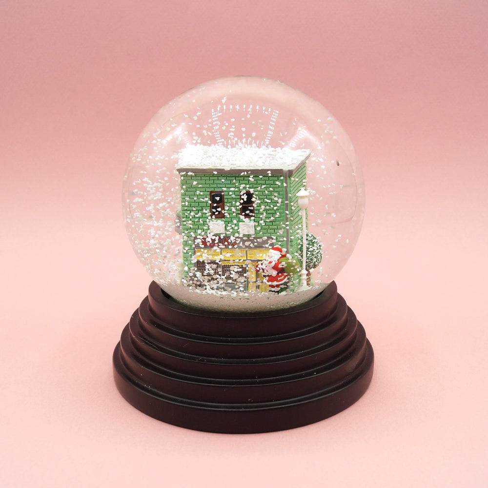 a close up of the custom designed snow globe on a pink background.