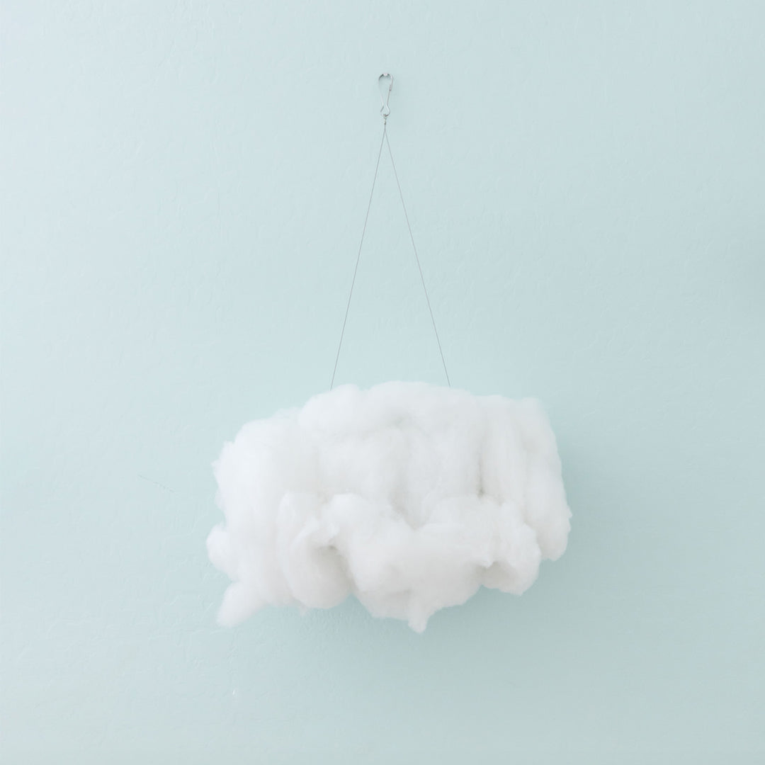 a cloud light hangs in the off position against a blue wall.