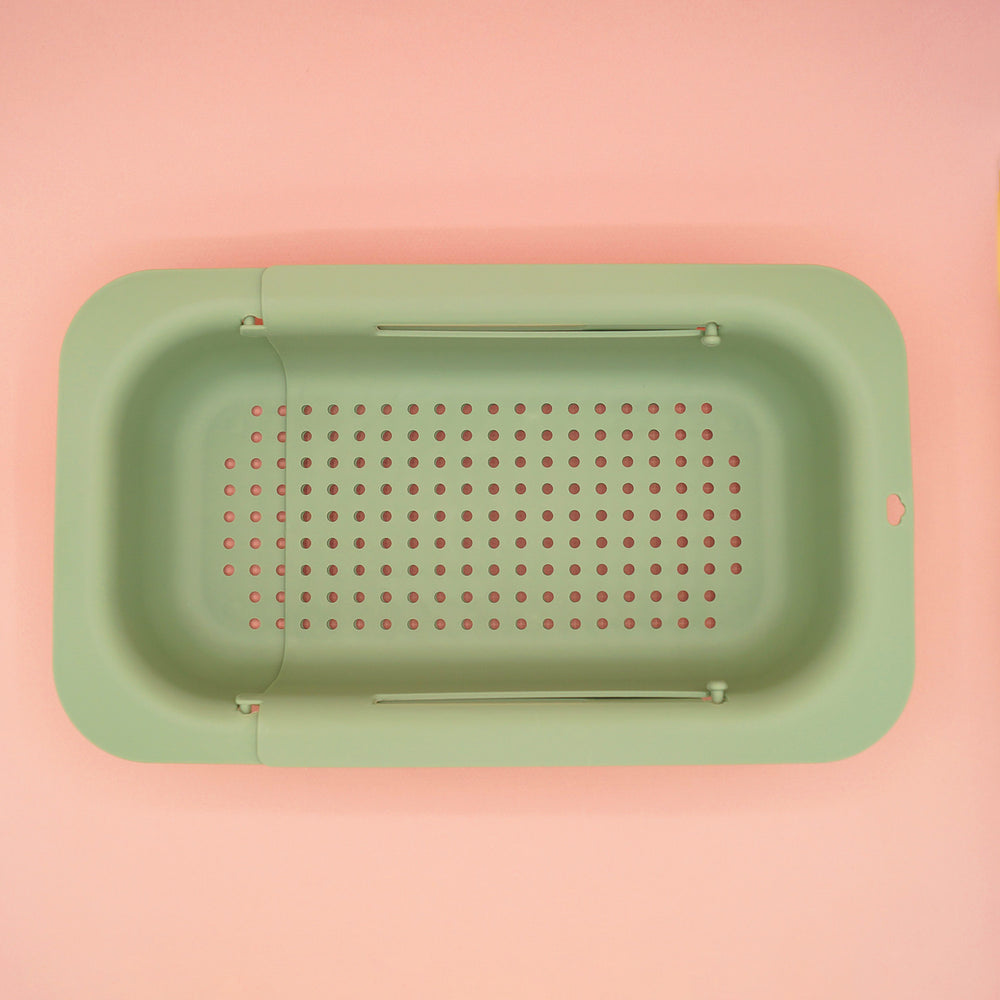 a pale green extendable colander on a pink background.