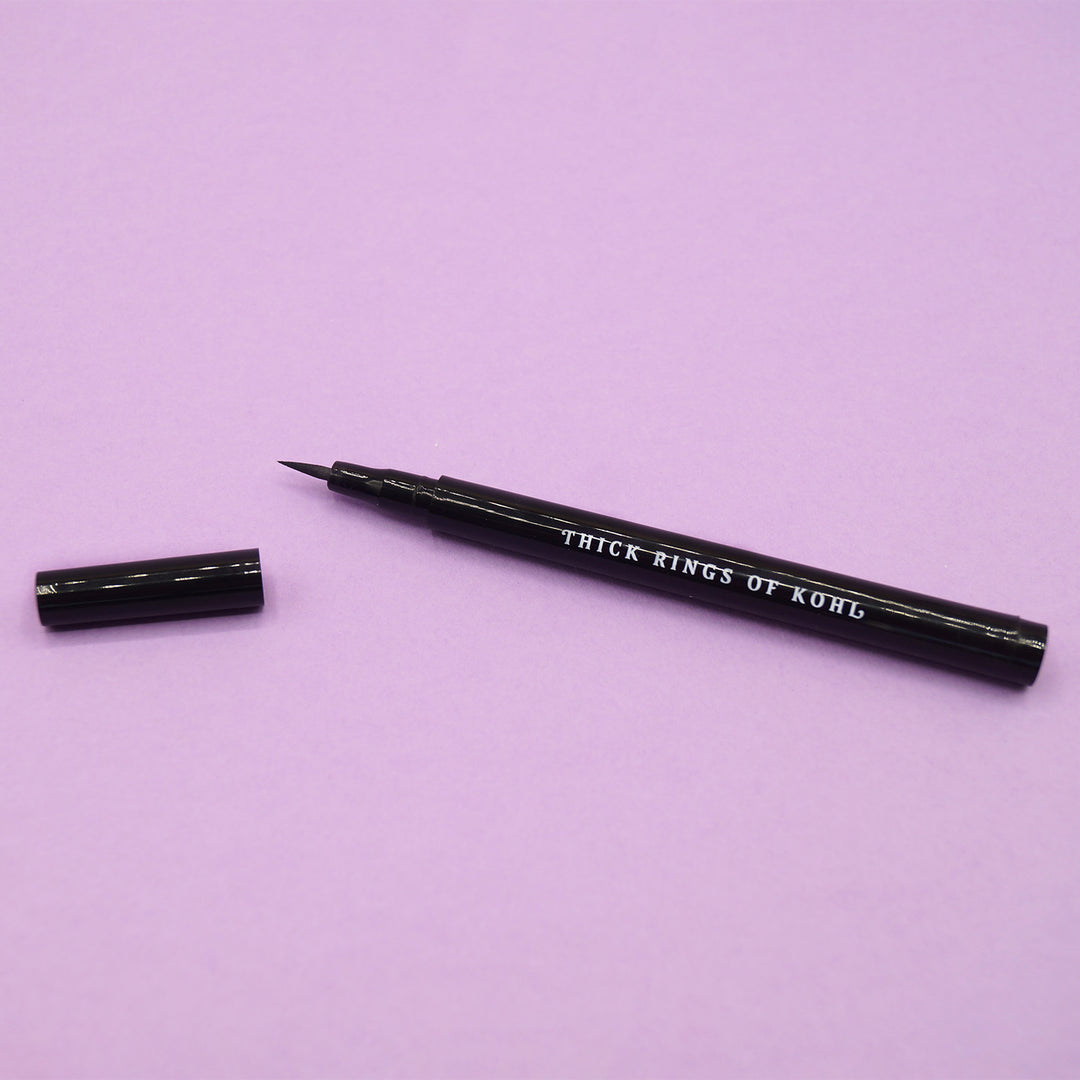 An open tube of black felt-tip eyeliner that says Thick Rings of Kohl on the side in white letters