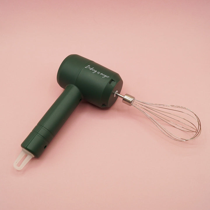 a wireless, dark green hand mixer with whisk attachment.