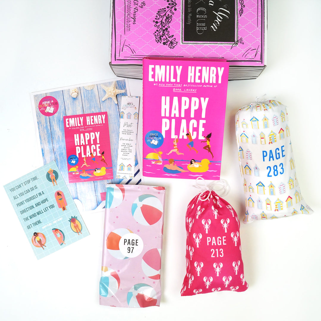 A pink Once Upon a Book Club box is at the top of the image. In front of the box are a hardcover edition of Happy Place, bookclub kit, bookmark, quote card, pink polybag with a beach ball pattern, pink drawstring bag with a lobster pattern, and a white drawstring bag with a pattern of houses. The boxes and bags all have page numbers.