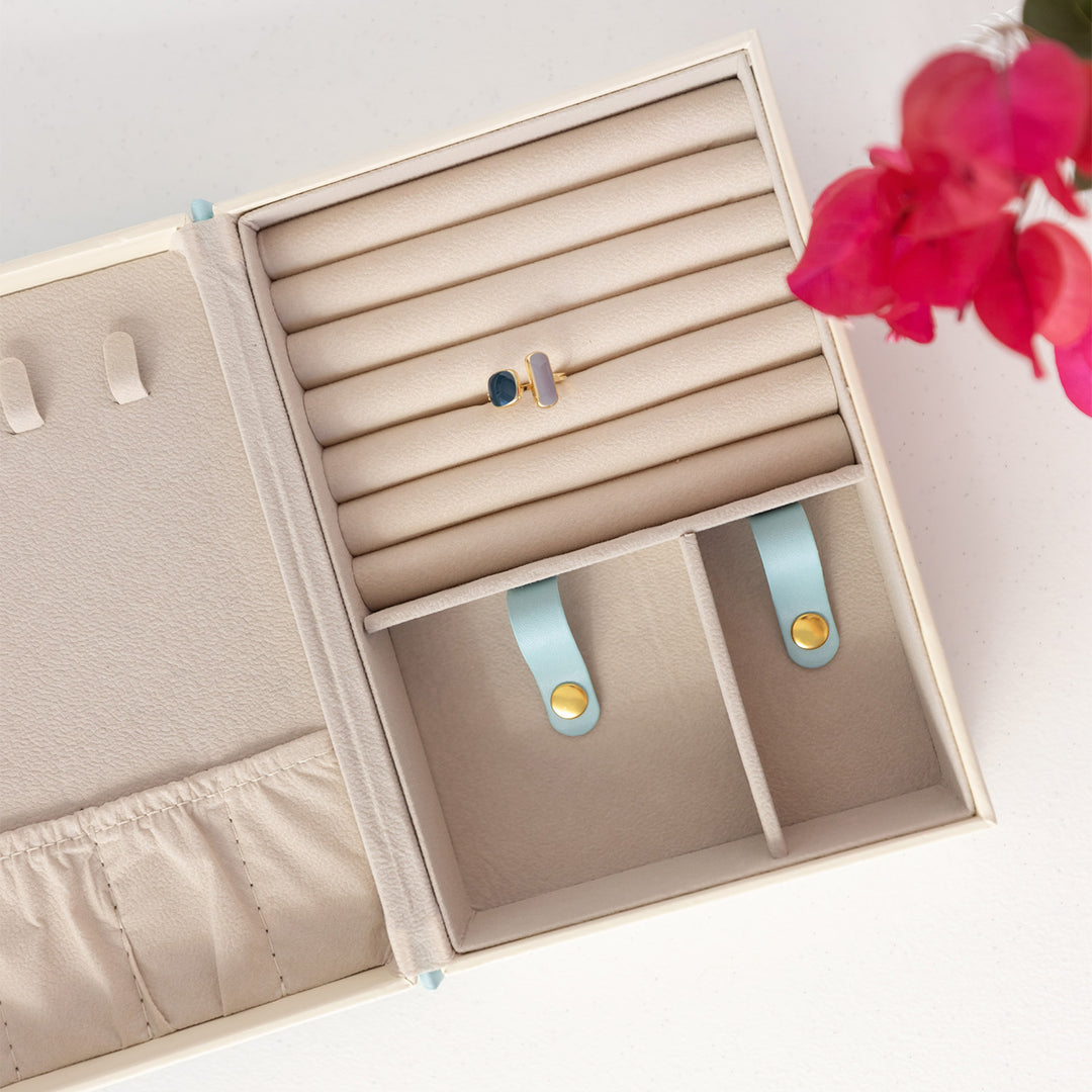 The interior of the book-shaped jewelry box featuring the ring and earring stud cushions and small necklace clips.