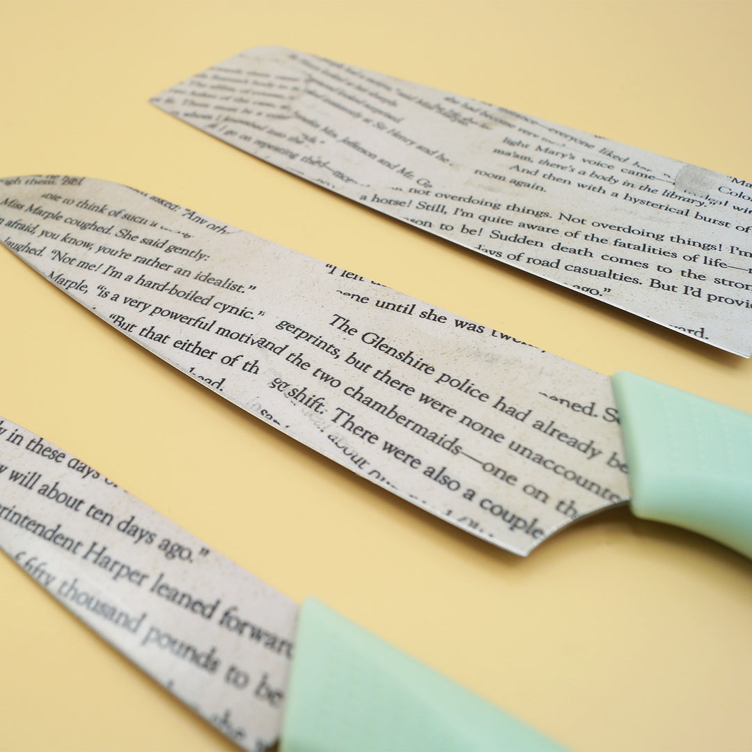 a set of three kitchen knives with seafoam green handles. The blades look like pages have been pasted onto them