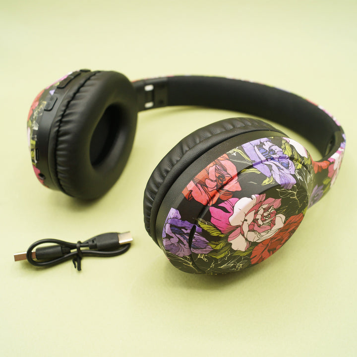 Black headphones with a floral pattern on the outside with flowers in purple, pink, and red colors.