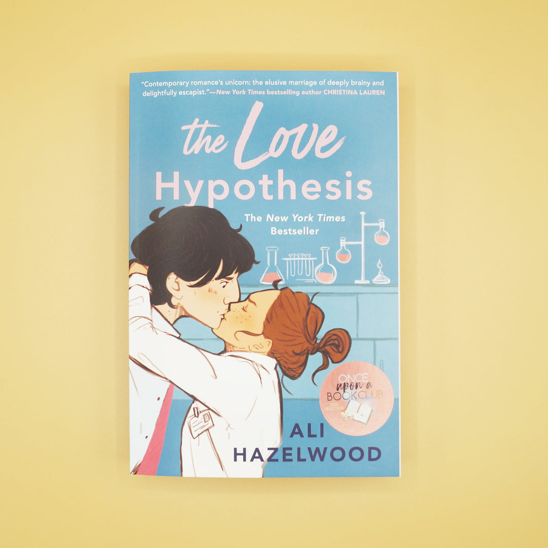 A paperback edition of The Love Hypothesis by Ali Hazelwood sits on a light yellow background.