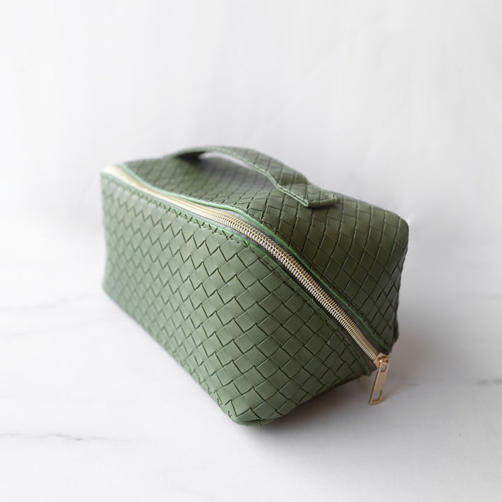 A green makeup bag sits closed with a gold zipper.