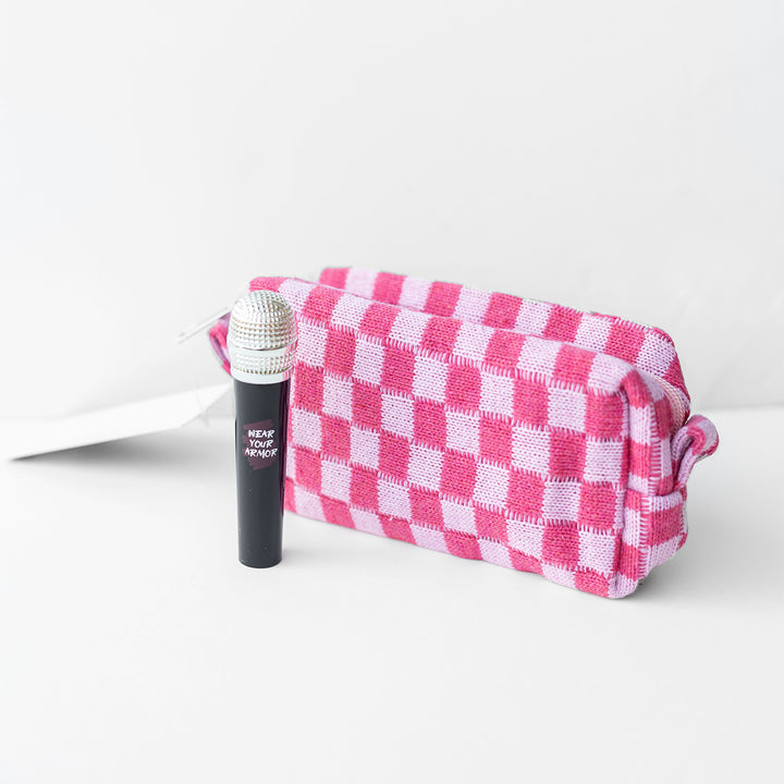 A pink checkerboard-patterned makeup bag and a microphone shaped lipgloss tube.