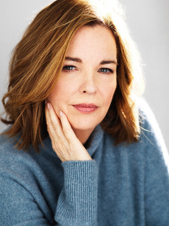 Author Martha Hall Kelly is a middle-aged white woman with shoulder-length, light brown hair sitting with her hand leaning against her face. She is wearing a blue sweater.