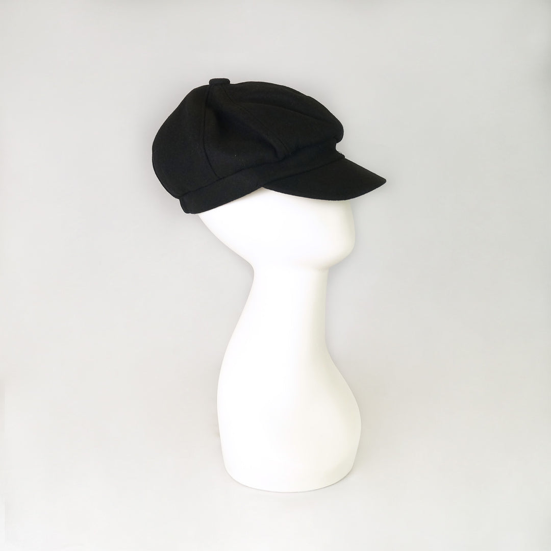 A white mannequin head wears a black newsboy cap