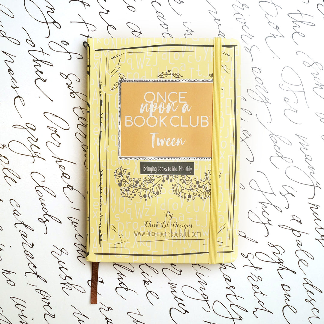 A yellow Once Upon a Book Club notebook sits on a white background decorated with script.