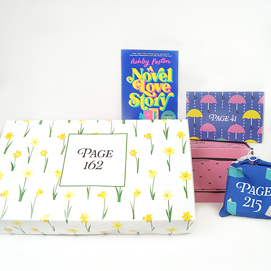 A paperback copy of A Novel Love Story by Ashley Poston sits on a pink Once Upon a Book Club adult box. This box is surrounded by wrapped gifts labeled with page numbers.