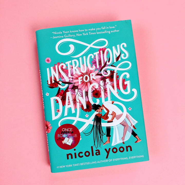 A hardcover copy of Instructions for Dancing by Nicola Yoon sits on a pink background.