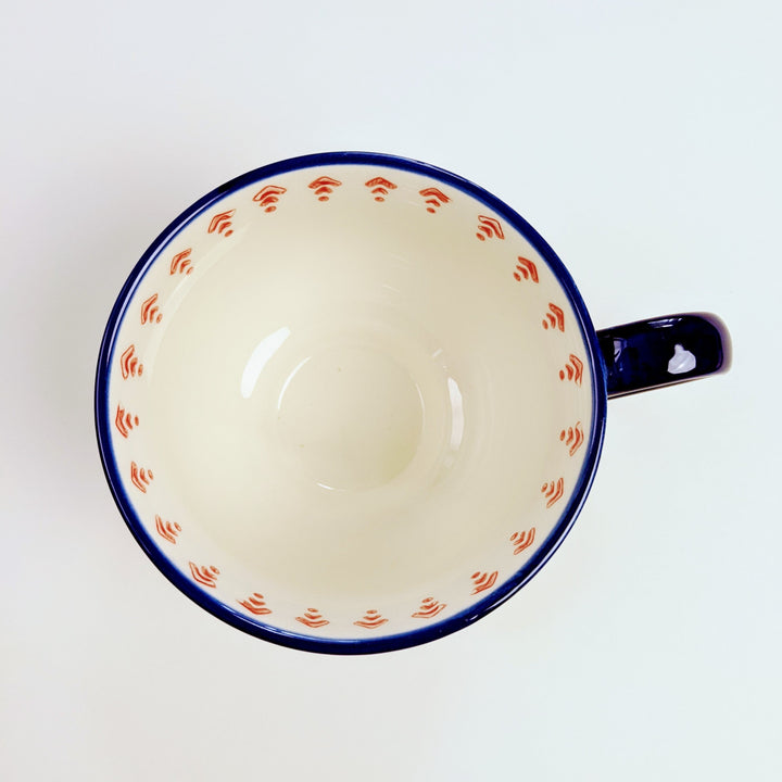A photo from above looking straight down into the oversized mug, showing the interior pattern of red triangles and the dark blue rim of the mug. On a white background.