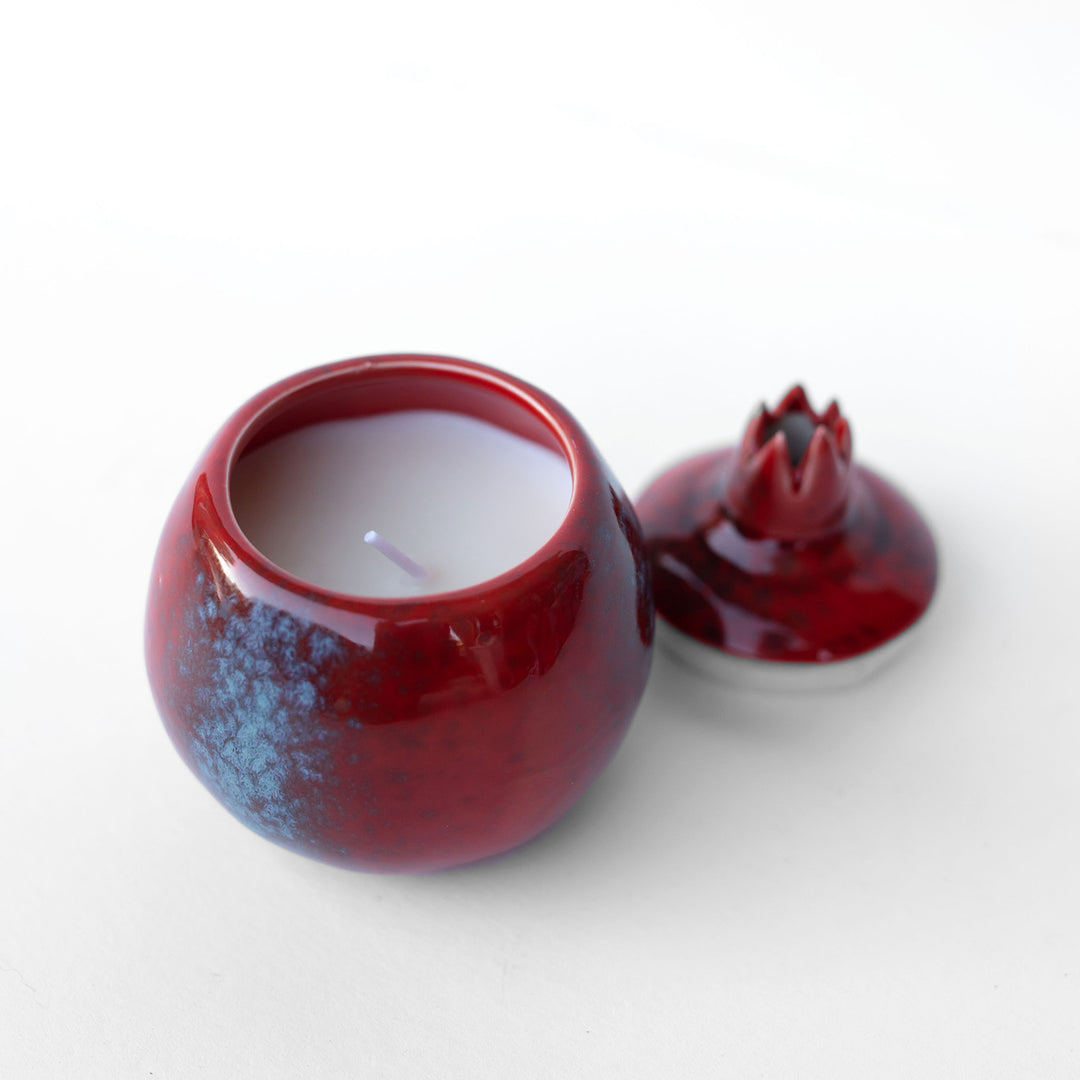 a pomegranate shaped ceramic candle with lid removed.