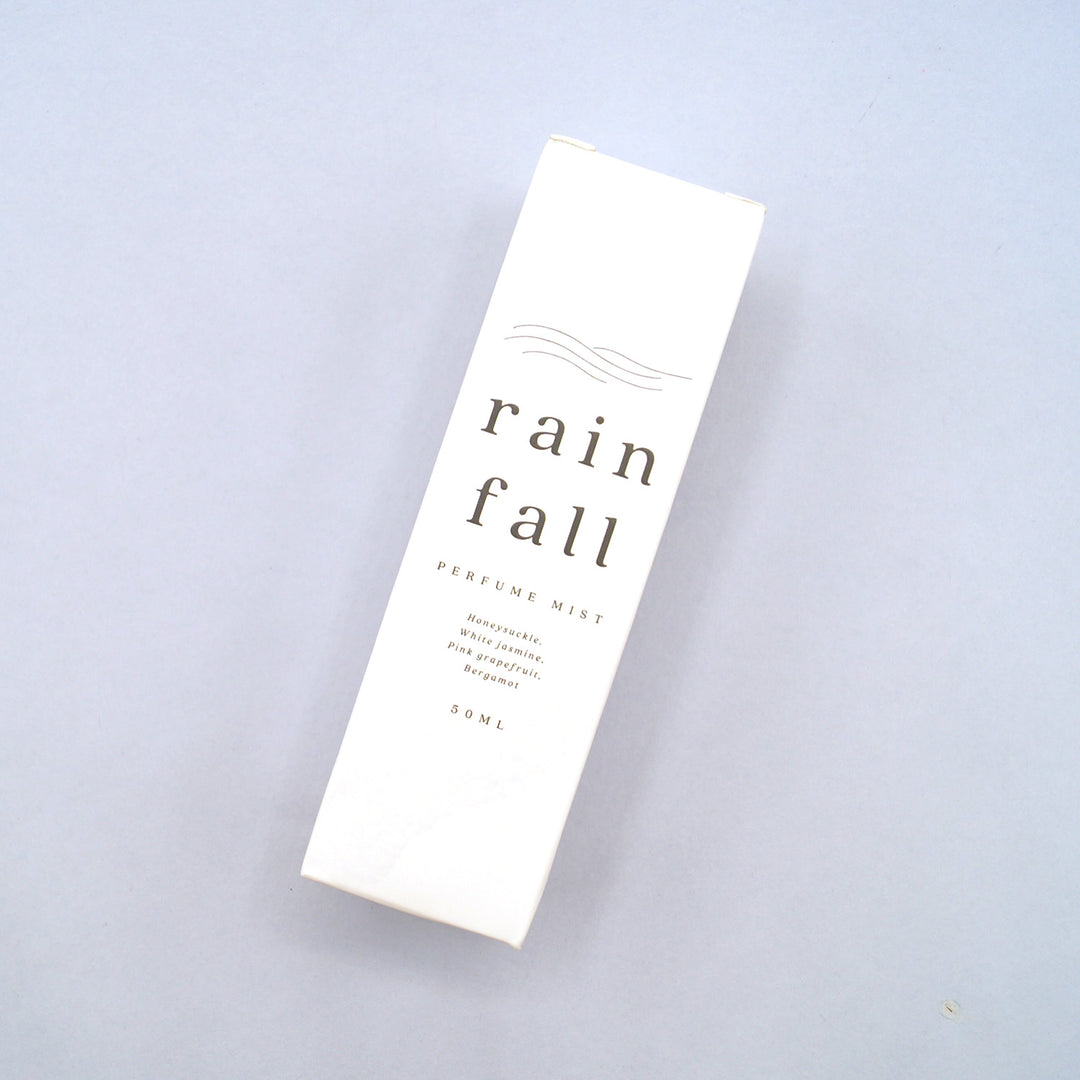 a custom box showing the details of the 'rain fall perfume mist' with notes of honeysuckle, white jasmine, pink grapefruit, and bergamot.