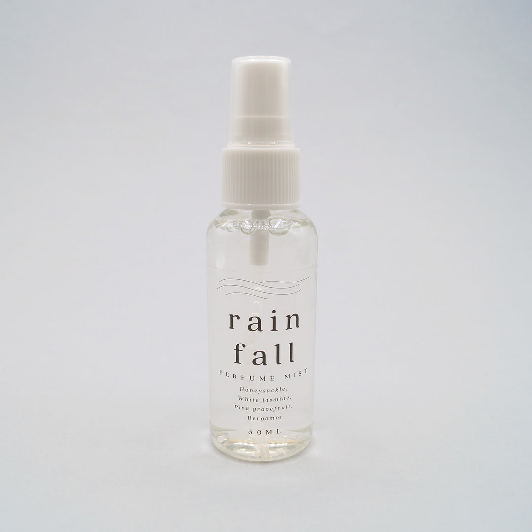 the bottle of rain fall perfume mist with notes of honeysuckle, white jasmine, pink grapefruit, and bergamot.