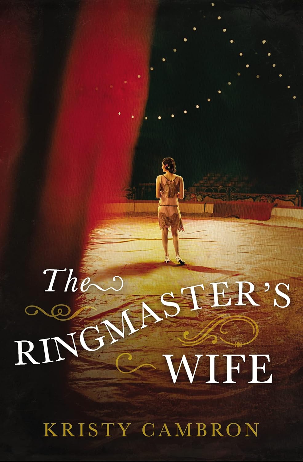 The book cover of The Ringmaster's Wife by Kristy Cambron. The cover features a woman standing at the center ring of a circus tent. The image appears to have been taken from partially behind a curtain.