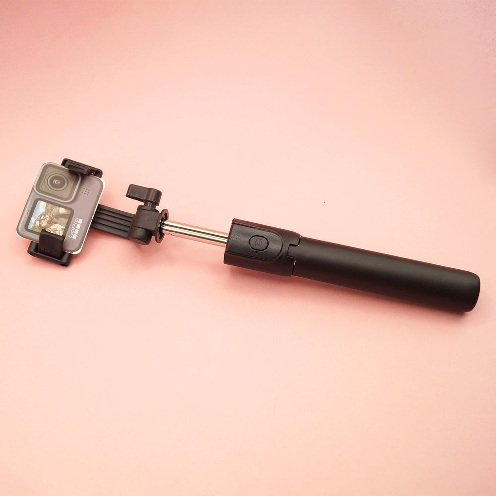 A black selfie stick with a piece of cardboard that looks like a camera in the spot where a phone is held.