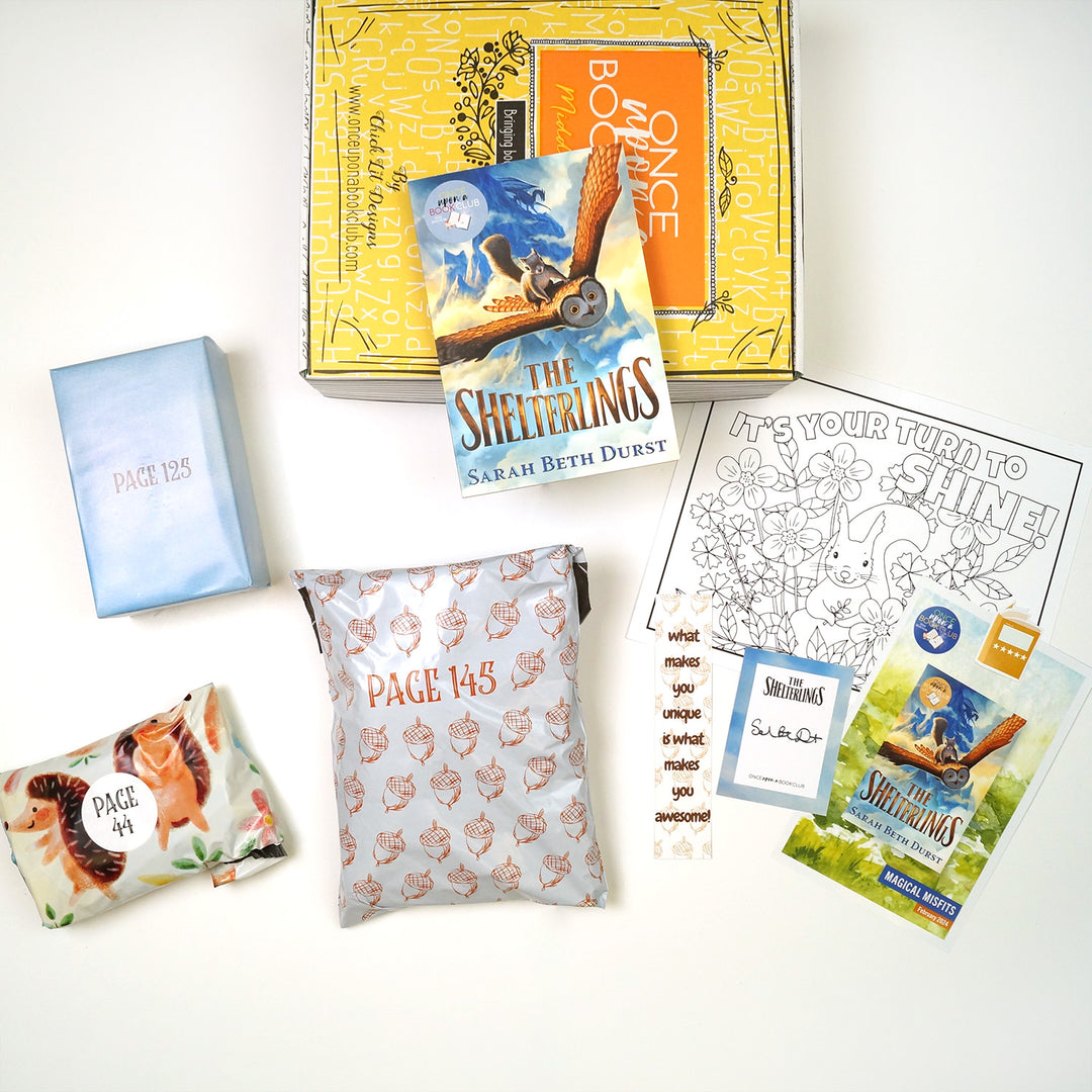 A paperback copy of The Shelterlings by Sarah Beth Durst sits on top of a yellow Once Upon a Book Club Middle Grade box. Surrounding this is three wrapped gifts labeled with page numbers, a signed bookplate, bookmark, coloring sheet, sticker, and reading flyer.