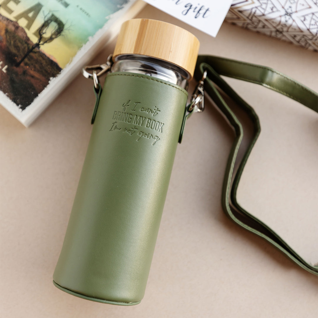 a glass water bottle in a leather travel case that reads "If I can't bring my book, I'm not going."