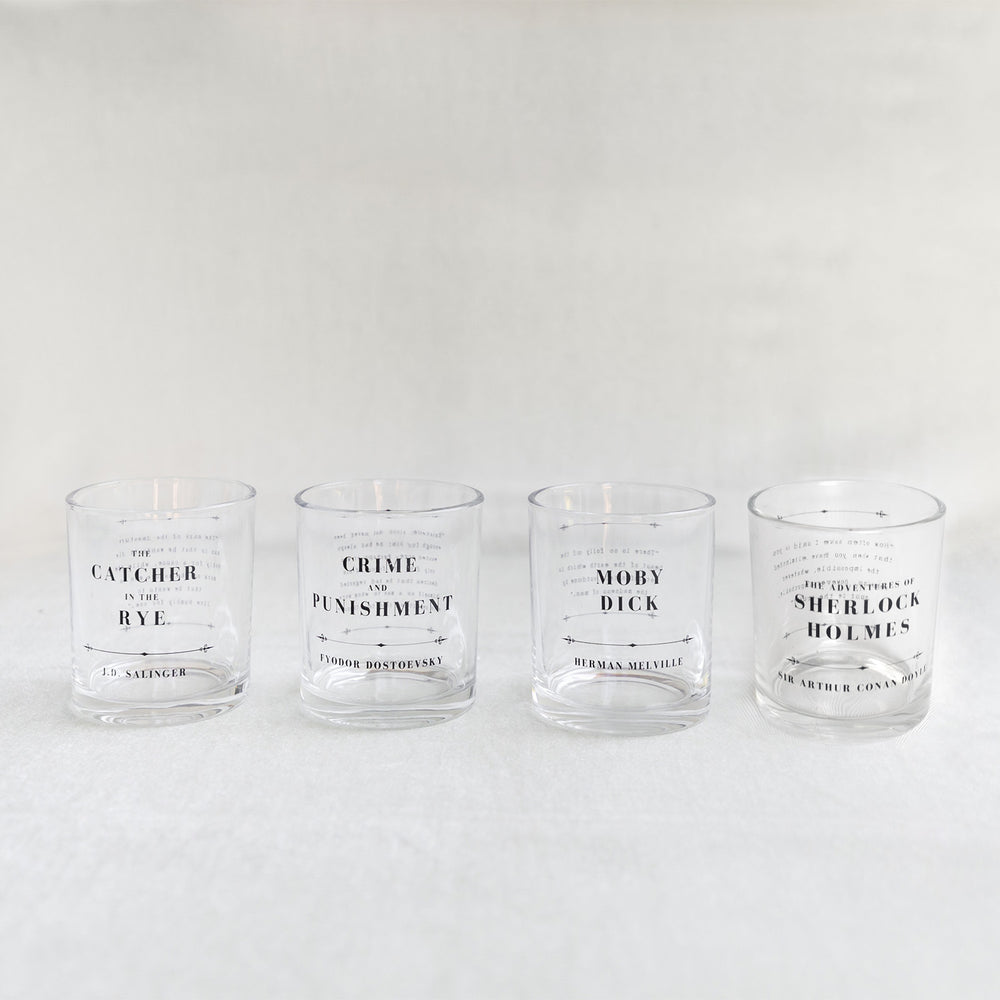 A set of whiskey glasses inspired by classic book titles. The four titles in order from left to right are The Catcher in the Rye by J.D. Salinger, Crime and Punishment by Fyodor Dostoevsky, Moby Dick by Herman Melville, and The Adventures of Sherlock Holmes by Sir Arthur Conan Doyle.